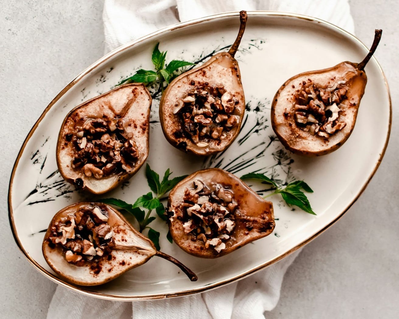 a white plate topped with sliced pears next to a bowl of nuts